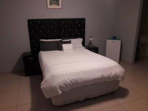una camera da letto con un grande letto con lenzuola e cuscini bianchi di Jessma Bed and Breakfast a Walvis Bay