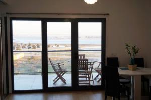 a room with a sliding glass door with a table and chairs at Apartment with view on Lisbon Tage & swimming pool in Seixal