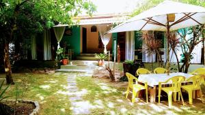 a table and chairs with an umbrella in front of a house at Chale Kangaroos Imbassai in Imbassai