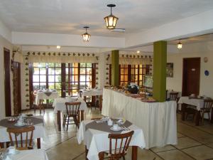 a dining room with white tables and chairs and windows at Alpenhaus Pousada in Campos do Jordão