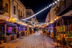 una calle por la noche con luces, mesas y sillas en Hotel Adora, en Tiflis