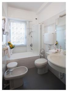 uma casa de banho branca com uma banheira, um WC e um lavatório. em Casavacanze Internazionale em Diano Marina