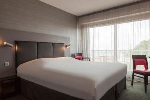 a large white bed in a room with a large window at Hôtel Le Nautic in Arcachon