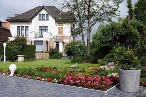 a house with a garden with flowers in front of it at Hotel La Roseraie in Wemmel