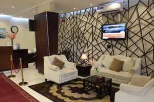 a lobby with two chairs and a tv on a wall at المهيدب 1 للشقق المخدومة - اقتصادى in Buraydah
