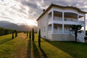 a house in a field with cypress trees at Olympos Sunset Residence - Mountain and Sea View in Litochoro