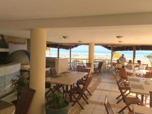 a restaurant with tables and chairs and a view of the ocean at Pipa's Bay Flats in Pipa