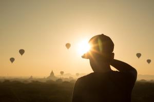 a man looking at the sunrise with hot air balloons at Ostello Bello Bagan in Bagan