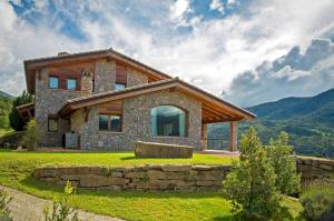 a stone house on a hill with mountains in the background at Serrat del Vent - Adults only in Ribes de Freser