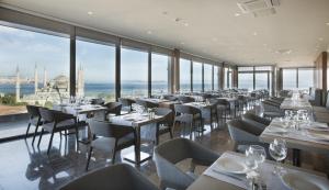 a restaurant with white tables and chairs and windows at Hotel Arcadia Blue Istanbul in Istanbul