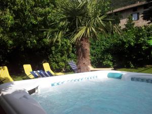 a swimming pool with chairs and a palm tree at Garni Meinrad in Auer