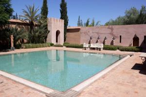 a swimming pool in a yard with chairs and a building at Palais Claudio Bravo in Taroudant