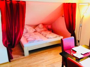 ウールディンゲン・ミュールホーフェンにあるLoftの赤いカーテン付きのベッドが備わる小さな客室です。