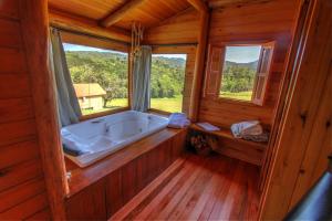 bañera en una habitación de madera con ventanas en Hospedaria Refugio do Invernador, en Urubici