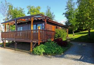 a small cabin with a large deck in front of it at Limestone Lodges in Bothel