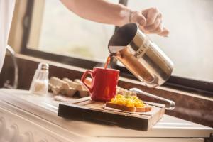 una persona che versa il caffè in una tazza rossa di Papachos Hostel a Baños