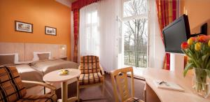 フランチシュコヴィ・ラーズニェにあるHotel Metropolのベッド、テーブル、窓が備わる客室です。