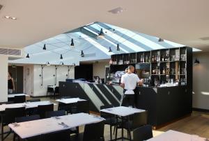 a man standing behind a bar in a restaurant at Maison Nô - Hôtel et Rooftop in Lyon