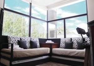 Habitación con 2 sofás frente a ventanas grandes. en Limay Bed&Breakfast en Neuquén