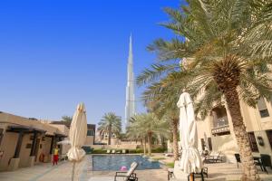 a pool with umbrellas and palm trees and a mosque at bnbmehomes Elegant Escape Downtown Opp to Burj - 504 in Dubai