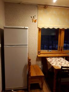 a kitchen with a refrigerator and a table and a window at 12 Pargi in Narva-Jõesuu