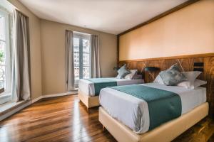 two beds in a room with wooden floors and windows at Rossio Boutique Hotel in Lisbon