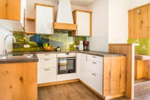 a kitchen with white cabinets and wood floors at Unterrainhof in Kleinarl