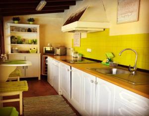 a kitchen with white cabinets and a sink and yellow tiles at Casa Rural Ceiba in El Rosario