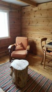 a living room with a chair and a tree stump at Tiny house with Fjordview! in Lauvstad