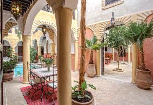 a courtyard with tables and potted plants in a building at Riad Itrane in Marrakesh