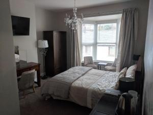 a bedroom with a bed and a desk and a window at Lion House Bed & Breakfast with Restaurant in Combe Martin