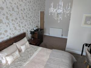 a bedroom with a bed and a chandelier at Lion House Bed & Breakfast with Restaurant in Combe Martin