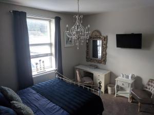 a bedroom with a bed and a mirror and a chandelier at Lion House Bed & Breakfast with Restaurant in Combe Martin