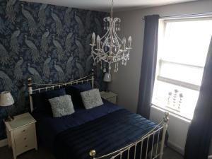 a bedroom with a blue bed and a chandelier at Lion House Bed & Breakfast with Restaurant in Combe Martin