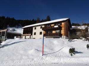 a building in the snow with a red pole at Tgantieni Sot - Apartment mit Herz in Lenzerheide +10 photos
