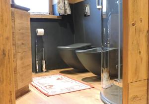 baño con aseo negro y lavamanos en Haus Martina, en Sappada