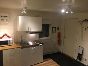 a kitchen with white cabinets and a sink and a microwave at Camp Caroli Wooden Cabins in Jukkasjärvi