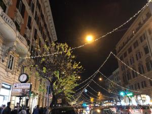 ローマにあるCola di Rienzo Innのクリスマスライトと時計が並ぶ賑やかな街道