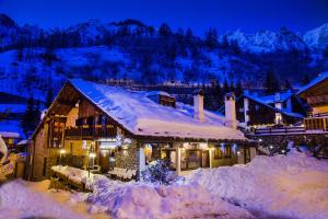 a house covered in snow at night at Hotel Pilier D'Angle & Wellness in Courmayeur