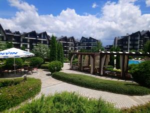 a patio with an umbrella and tables and chairs and buildings at Studio L006 in Aspen Golf in Bansko