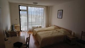 a bedroom with two beds and a table and a window at Studio L006 in Aspen Golf in Bansko