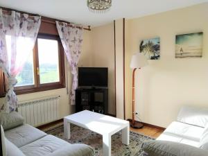 a living room with two white couches and a tv at Casa Bahía Santander in Pedreña