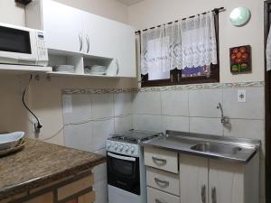 una pequeña cocina con fregadero y microondas en RESIDENCIAL COM CASAS DE 3 DORM, en Garopaba