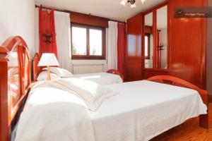1 dormitorio con 2 camas blancas y ventana en Casa Bahía Santander, en Pedreña