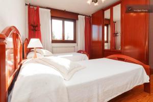 a bedroom with two white beds and a window at Casa Bahía Santander in Pedreña