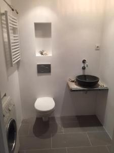 a white bathroom with a toilet and a sink at ZILT sous in Noordwijk