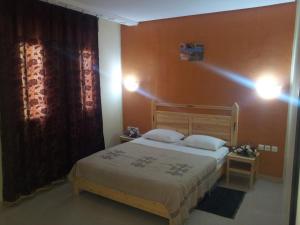 1 dormitorio con cama y pared roja en Résidence El Arich, en Tozeur