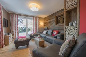 a living room with leather couches and a wooden wall at Chalet Alpin in Oberstdorf