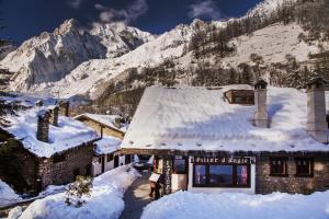 a building covered in snow with a mountain in the background at Hotel Pilier D'Angle & Wellness in Courmayeur