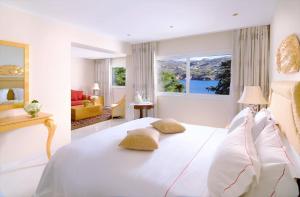 a bedroom with a large white bed and a window at Out Of The Blue Resort & Spa in Agia Pelagia